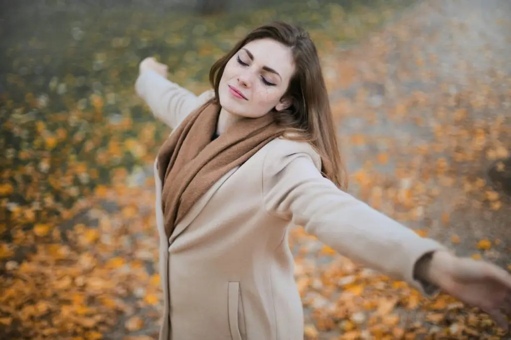 A woman with a smile opens her arms in the street showing her trust and confidence gained after receiving French Language Coaching with FeelGoodFrench