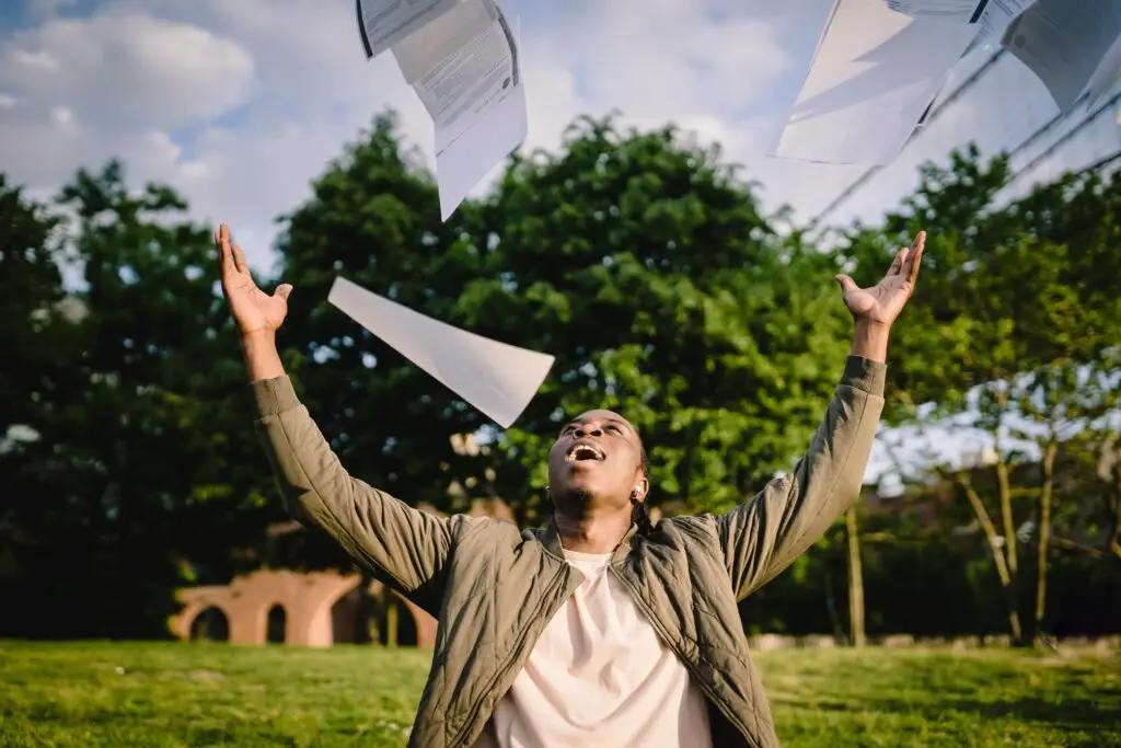 A man is showing a sense of relief while throwing in the air his DELF or DALF exam papers in a gesture of success. He made it and passed the French test with total success!