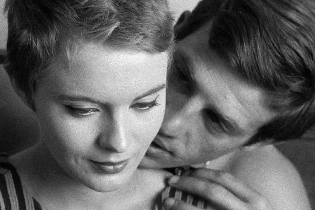 Two beautiful actors in black and white sit on a bed with some tenderness calling each others "my lover" in French.