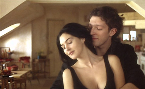 A tender moment from L’Appartement (The Apartment) (1996). Vincent Cassel embraces Monica Bellucci, his nose close to her ear, eyes closed, and a soft smile on his face. The intimacy of the gesture captures the depth of their connection and unspoken emotions.