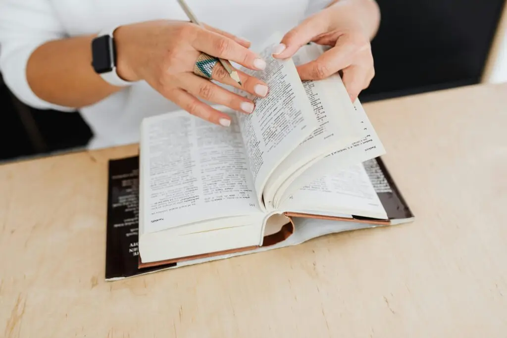 Close-up of hands flipping through a medical dictionary, symbolizing the journey of mastering medical French vocabulary and terms online.