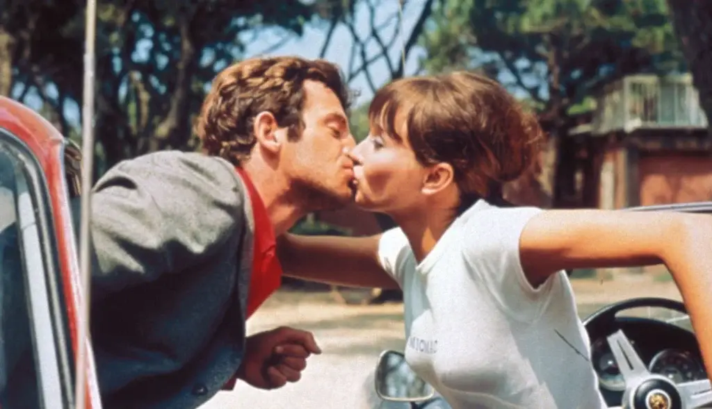 A couple French kiss while sitting in different cars. One of the most iconic romantic scene in French cinema