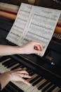Close-up of a woman's hands on a piano, turning sheet music pages, capturing musical focus.