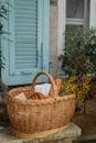 A charming wicker basket with fresh bread and croissants beside a shuttered window.