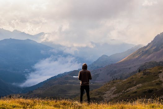 pexels-photo-3163927-3163927 A lone hiker stands in awe of the misty mountain landscape in France.