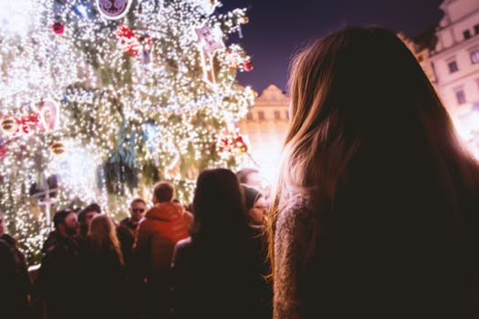 People enjoying a festive Christmas celebration with illuminated trees and joyful atmosphere at night.