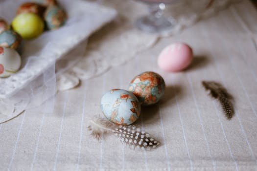 Colorful Easter eggs and feathers on a linen tablecloth, evoking seasonal cheer.