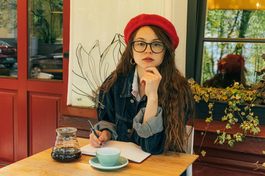 A learner with a notebook in a bright café for positive French phrases.