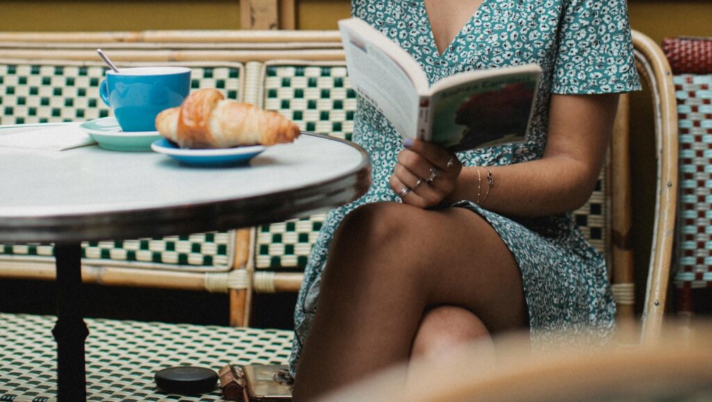 A relaxed learner reading a French book with coffee nearby.