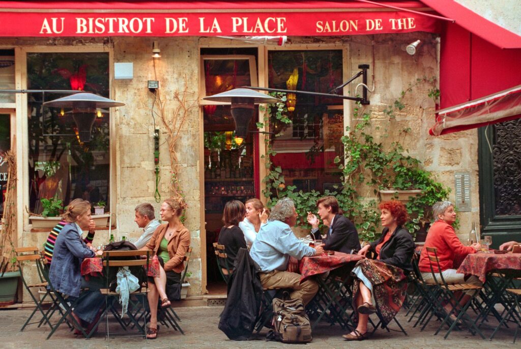 Expatrié discutant naturellement avec des habitants dans un café ou un marché en France.