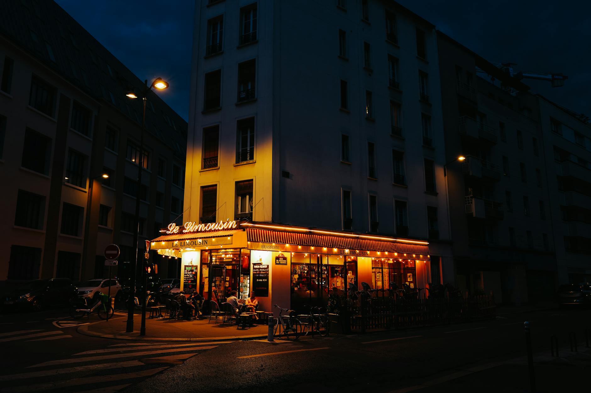Salutation amicale devant un café français dans la lumière du soir.