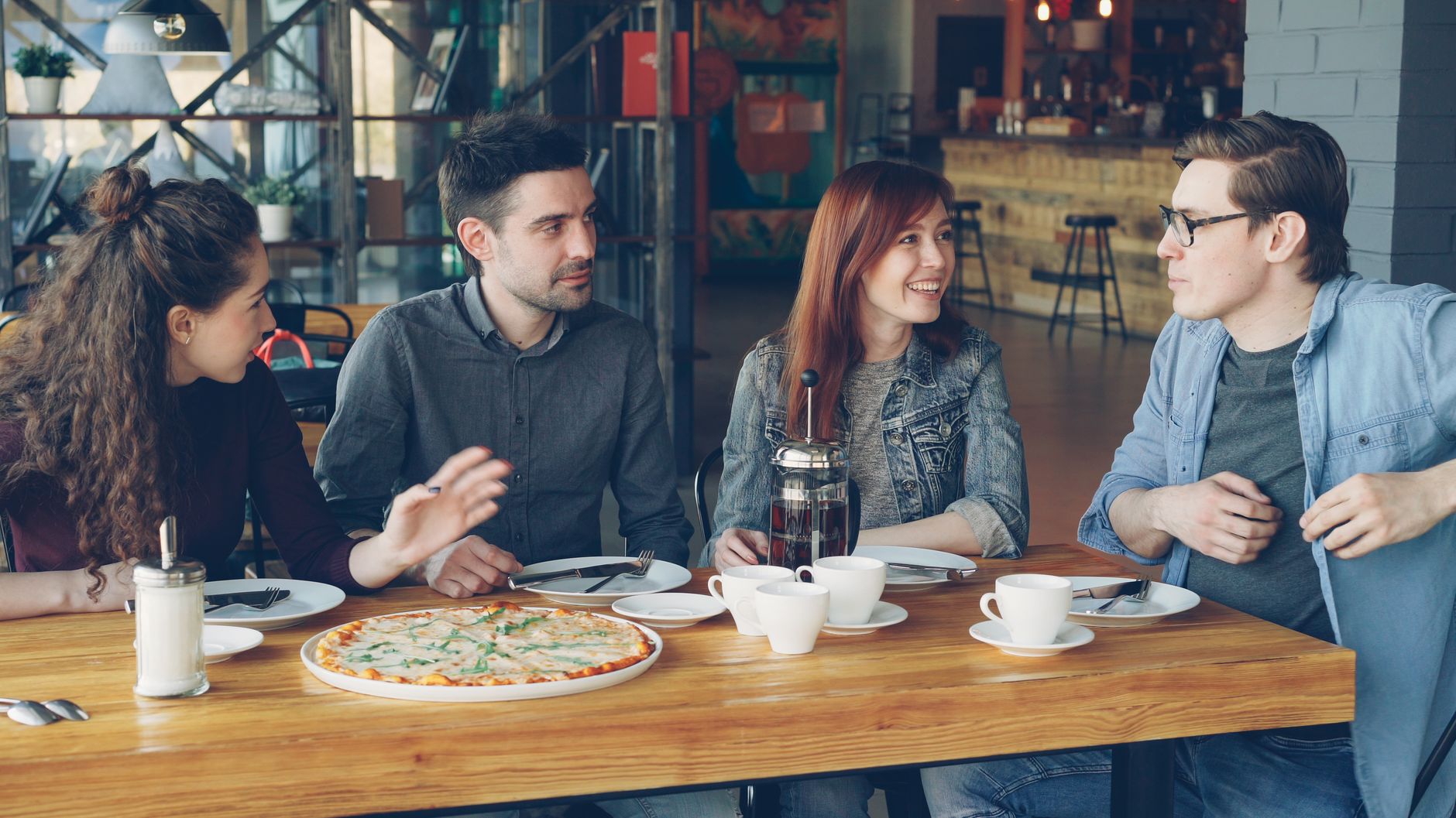 Friends chatting in a café for learning natural everyday French expressions.