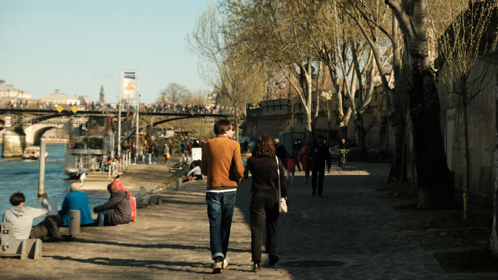 A couple walking hand in hand by the Seine in Paris.