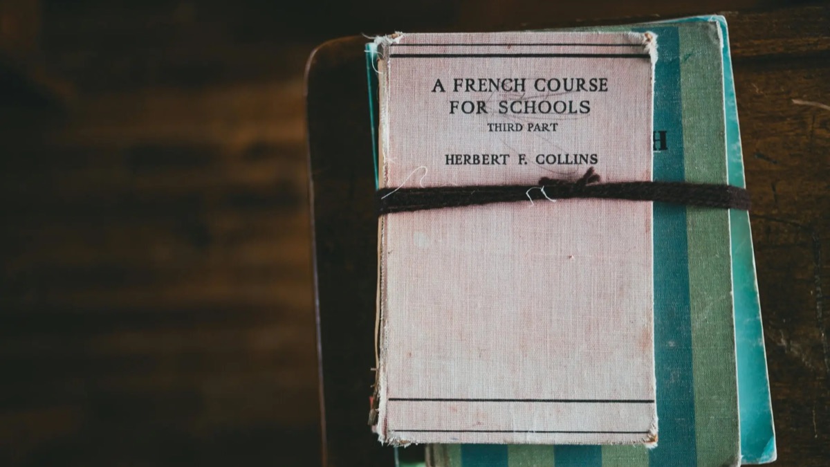 Parent préparant des documents d’inscription scolaire avec un cahier de français.