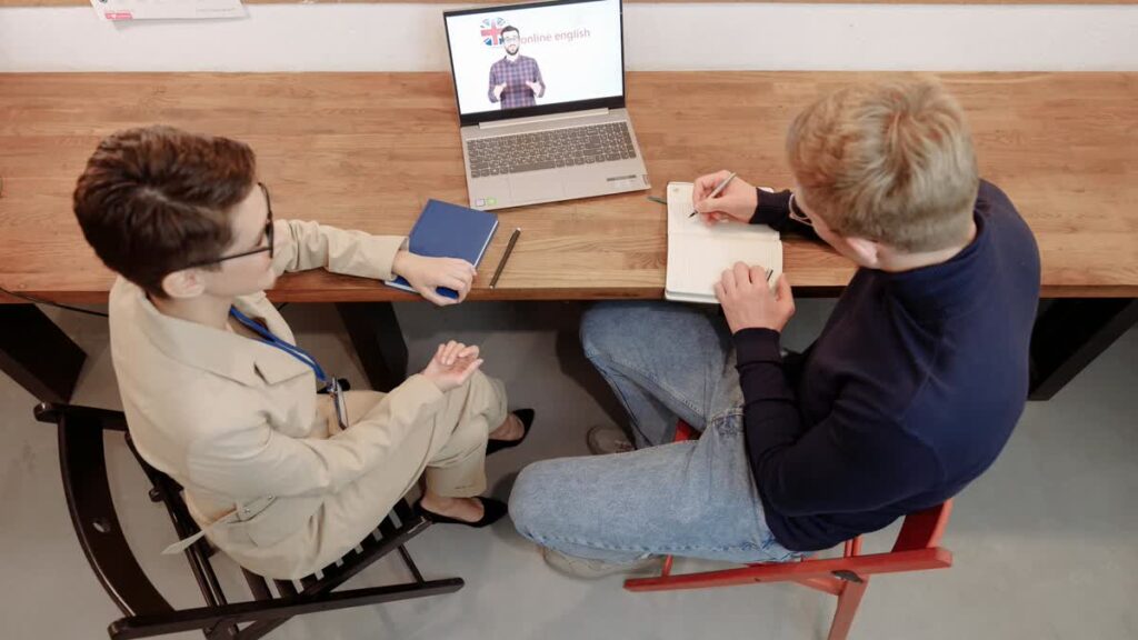 Adult learner taking notes during an online language coaching session.