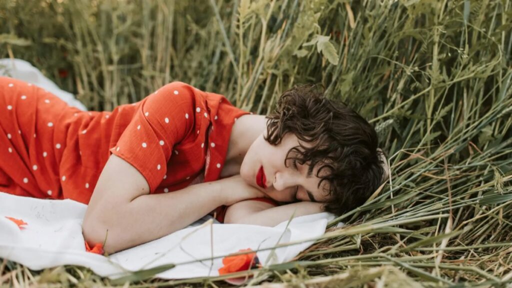 Femme endormie dans l’herbe, symbole des méditations guidées pour apprendre le français en douceur.