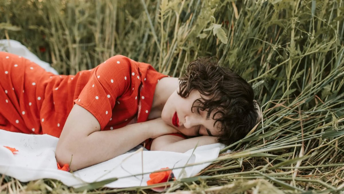 Femme endormie dans l’herbe, symbole des méditations guidées pour apprendre le français en douceur.