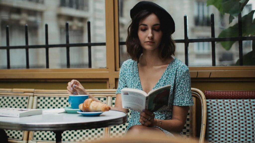 Étudiante lisant un roman français dans un café pour apprendre le français avec la littérature.
