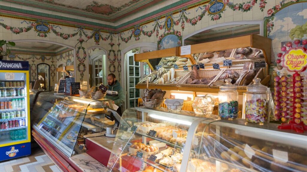 A person ordering bread at a French bakery counter with baguettes on display