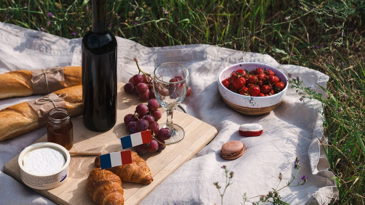A relaxed French picnic with bread, cheese, fruit, and shared food on a blanket outdoors.