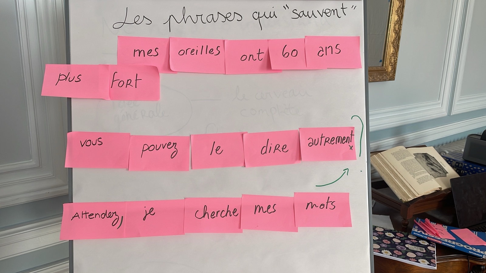 Pink notes on a French classroom whiteboard with useful phrases for keeping a conversation going