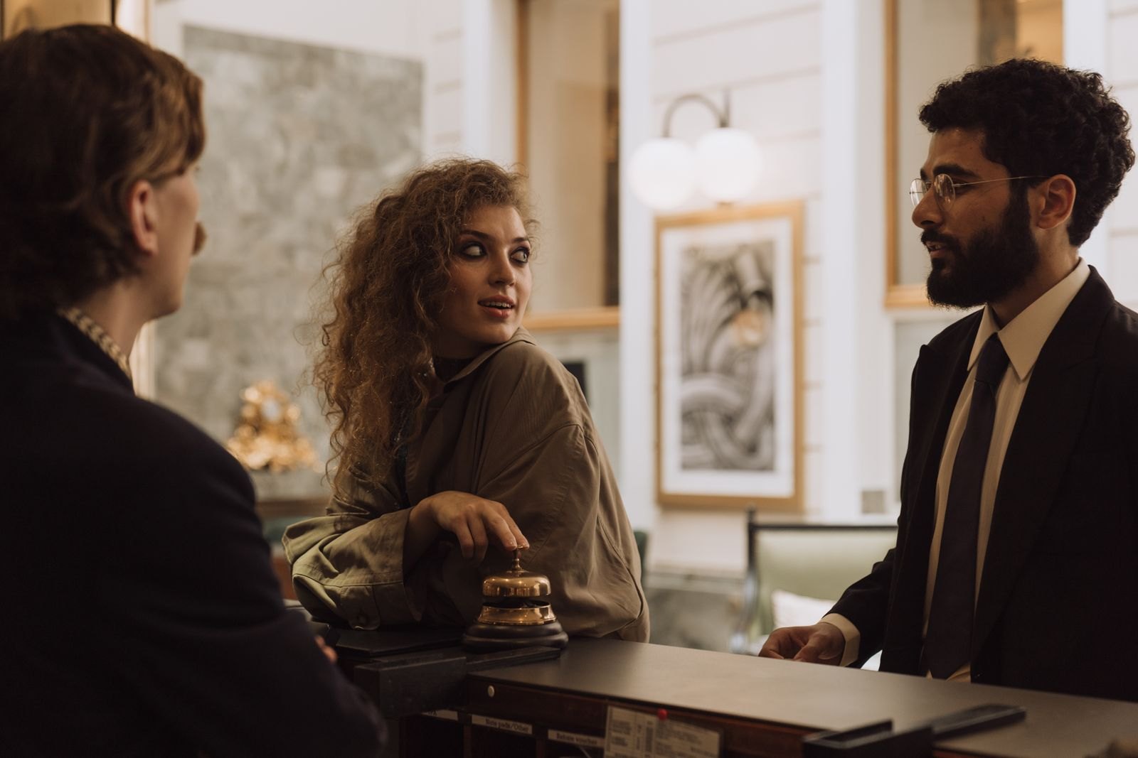 Hotel receptionist speaking with two guests across a reception desk