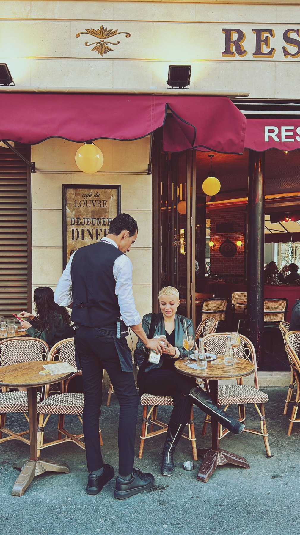 Waiter speaking with a guest at an outdoor café table in Paris