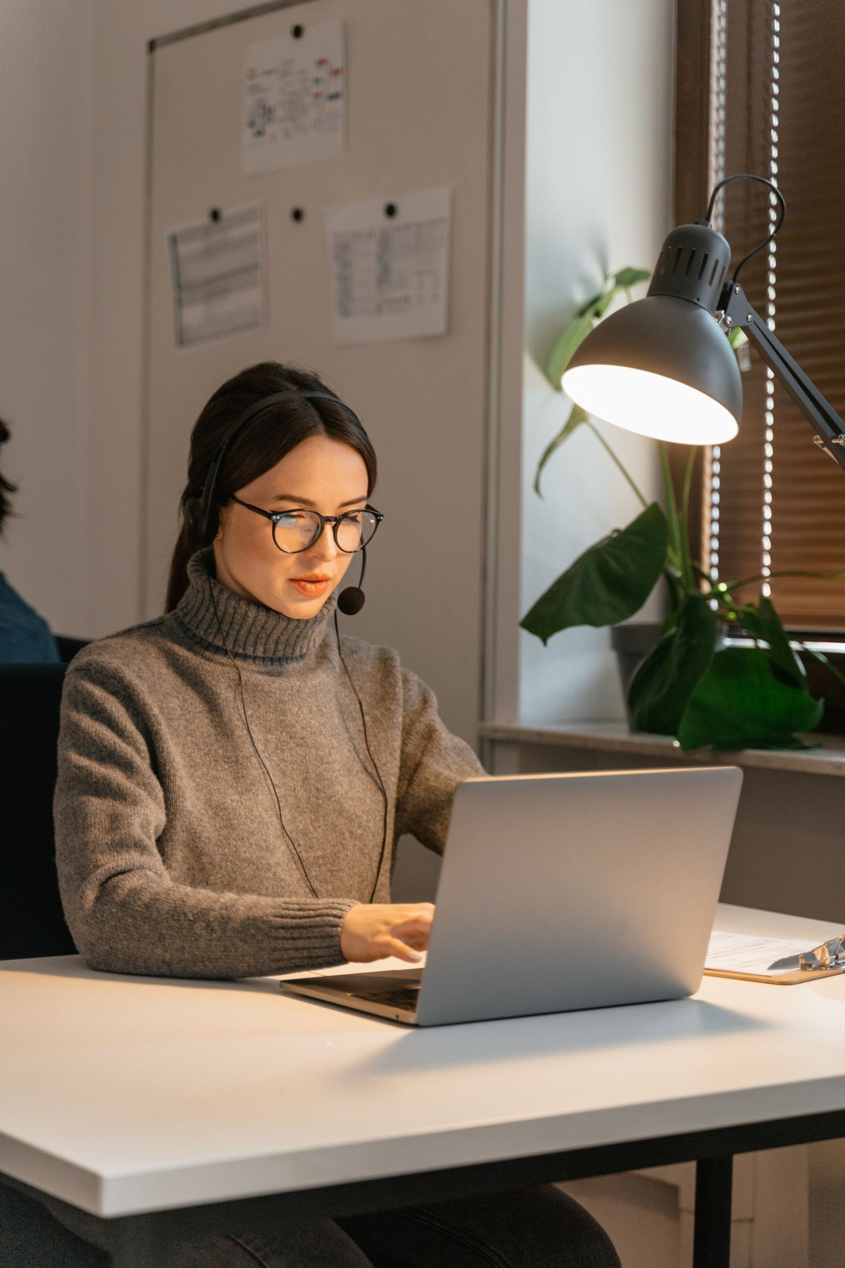 Customer-service professional using a headset and laptop at a desk